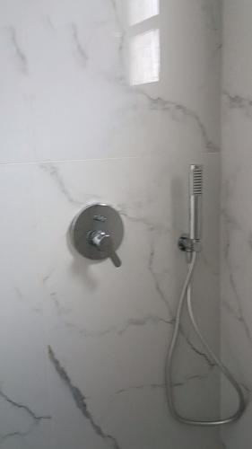a shower with a hose attached to a wall at Perissa Black Rock Lotus in Perissa