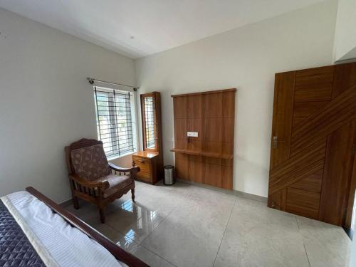 a bedroom with a chair and a wooden cabinet at May Flower Cottage in Ooty