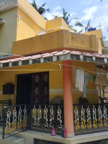a yellow house with a balcony with a fence at Rohini Homestay in Varkala