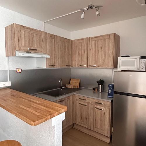 une cuisine avec des armoires en bois et un réfrigérateur en acier inoxydable dans l'établissement Séjour haut de gamme climatisé, spacieux, grand confort et terrasse, en famille ou entre amis, au Cap d'Agde