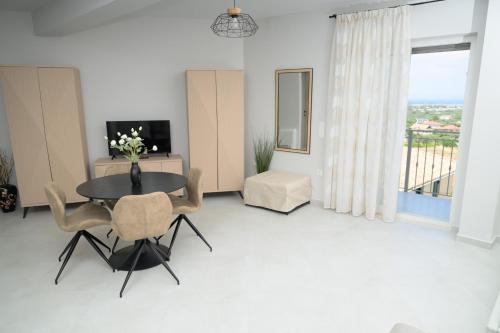 a living room with a table and chairs and a television at Sotale Suites in Apolpaina