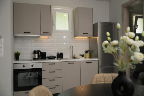 a kitchen with white cabinets and a table with a vase of flowers at Sotale Suites in Apolpaina