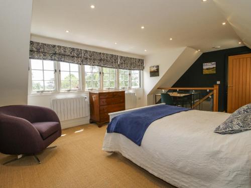 a bedroom with a bed and a chair and a desk at Garden Cottage in Ledbury