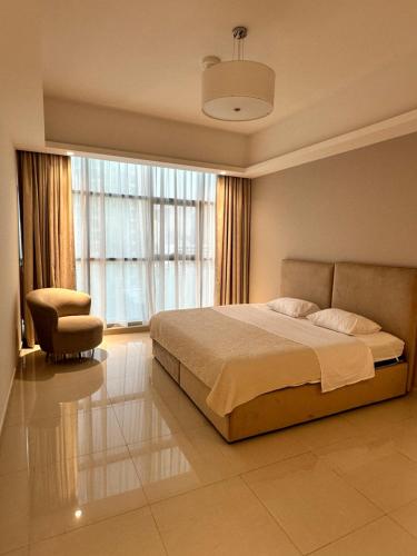 a bedroom with a bed and a chair and a window at Appartement 1BR de 2024 avec piscine et salle de sport in Ajman