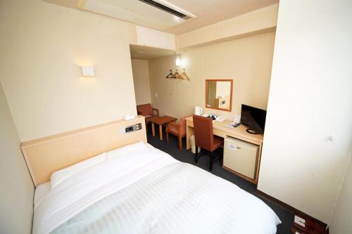 a room with a bed and a desk with a computer at Amami Port Tower Hotel in Amami