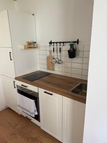 a small kitchen with white cabinets and a sink at Living and feeling good in Burgbernheim