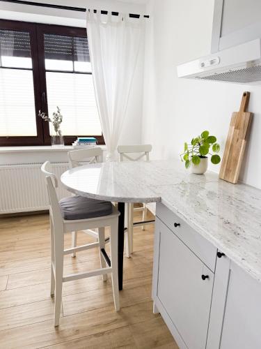a white kitchen with a white table and chairs at MERSEA in Ustka