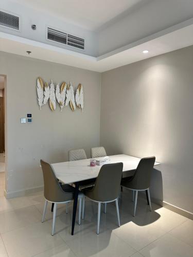a dining room with a white table and chairs at Appartement 1BR de 2024 avec piscine et salle de sport in Ajman