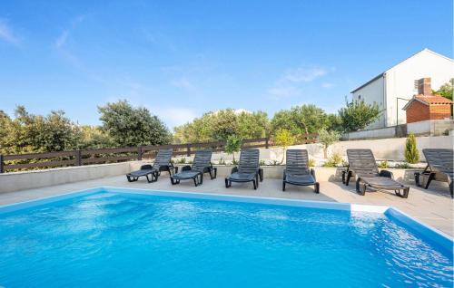 a swimming pool with chaise lounges and chairs next to a swimming pool at Awesome Home In Murter in Murter