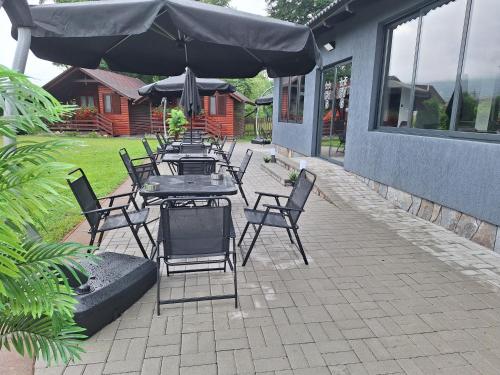 a patio with tables and chairs with an umbrella at Case de vacanță Gabriel in Sovata