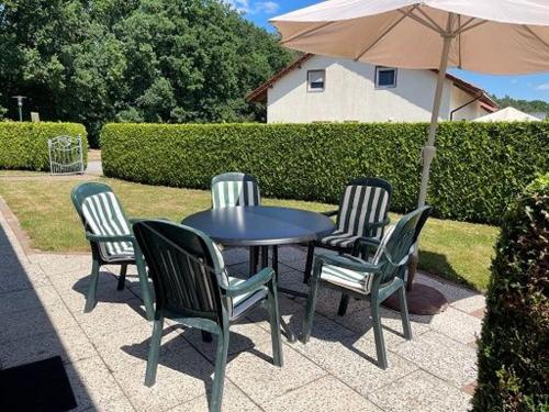 a table with four chairs and an umbrella at Ferienhaus Geers am Klostersee Dargun in Dargun