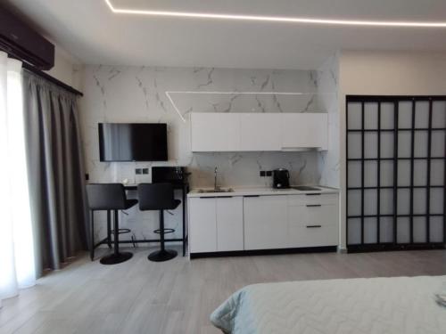 a white kitchen with two black chairs in a room at Frederica Luxury Apartments in Lagyná