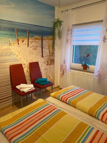 a bedroom with a bed and two chairs in front of a beach at Bungalow am Hellbach XL im Ostseeland in Neubukow