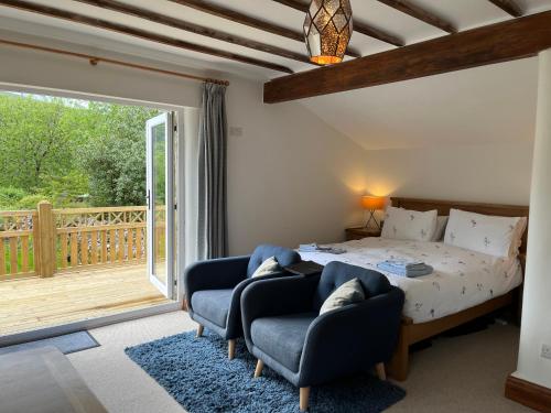 a bedroom with a bed and two chairs and a balcony at The Dale - Luxurious annexe with stunning view in Buckden