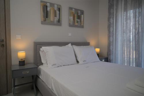 a bedroom with a white bed with two lamps on tables at Sotale Suites in Apolpaina