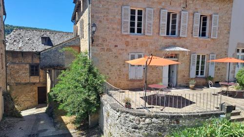 a building with tables and umbrellas in front of it at La Maison du Griffoul BB à Salles la Source cascade et terroir in Salles-la-Source