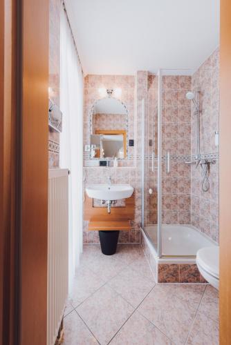 a bathroom with a sink and a shower and a tub at Ambienthotel Tassilo in Dingolfing