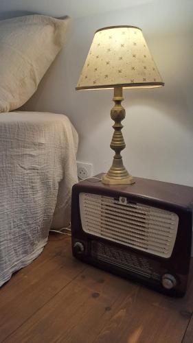an old radio with a lamp on top of it next to a bed at La Maison du Griffoul BB à Salles la Source cascade et terroir in Salles-la-Source
