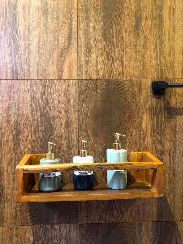 a wooden shelf with three soap dispensers on a wall at Tunnel Top Inn Ella in Ella