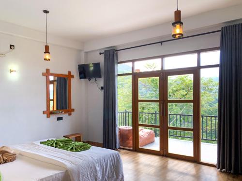 a bedroom with a large sliding glass door with a balcony at Tunnel Top Inn Ella in Ella