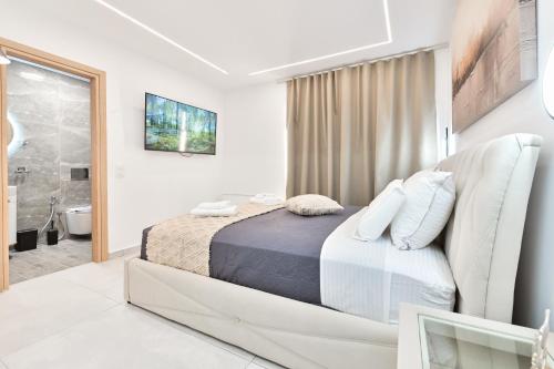 a white bedroom with a bed and a bathroom at September15 Suites- Meganisi in Meganisi