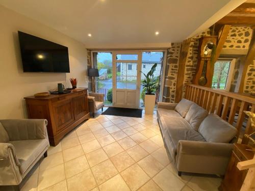 un salon avec un canapé et une télévision dans l'établissement Longère 7 personnes - 4 chambres - 3 SdB Orcival, à Vernines