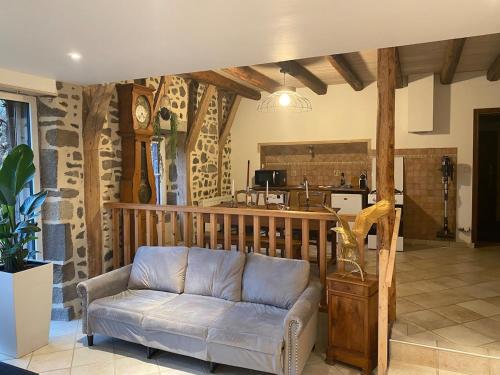 un salon avec un canapé et une cuisine dans l'établissement Longère 7 personnes - 4 chambres - 3 SdB Orcival, à Vernines