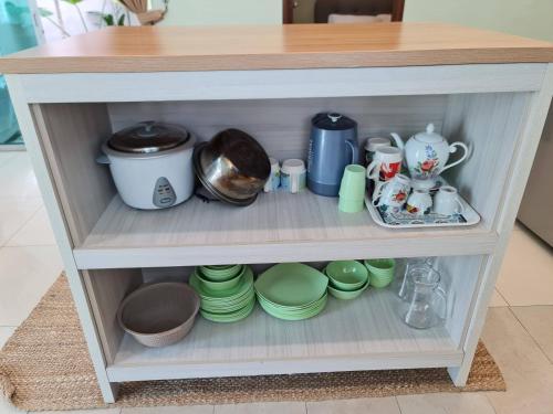a shelf with cups and dishes in a cabinet at Duyong Damai Homestay by KOWBMAS in Melaka