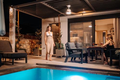 a woman in a dress standing next to a swimming pool at September15 Suites- Meganisi in Meganisi