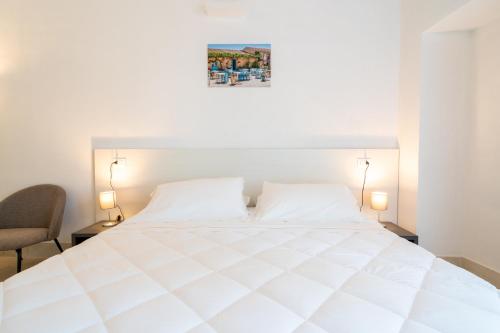a bedroom with a white bed and a chair at Borgo Vita Novella Resort in Marzamemi