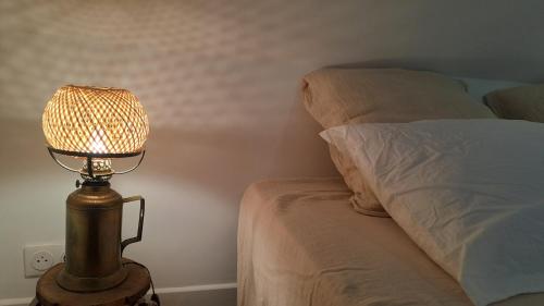 a lamp sitting next to a bed in a bedroom at La Maison du Griffoul BB à Salles la Source cascade et terroir in Salles-la-Source
