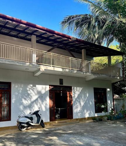 a scooter parked in front of a building with a balcony at Cecilia Unawatuna Rooms in Unawatuna