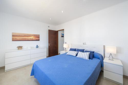 ein weißes Schlafzimmer mit einem blauen Bett und weißen Schränken in der Unterkunft Casa Can Picafort in Can Picafort