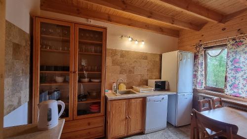 a kitchen with wooden cabinets and a refrigerator at Domki Na Wzgórzu in Nowica