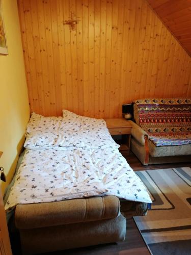 a bedroom with a bed and a couch in a room at Góralska Czarcia Chata pod Jałowcem in Stryszawa