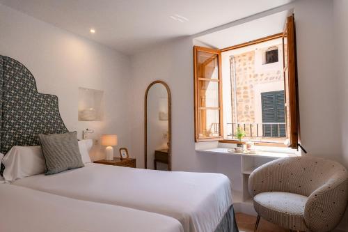 a bedroom with a bed and a chair and a window at Petit Biniaraix in Sóller