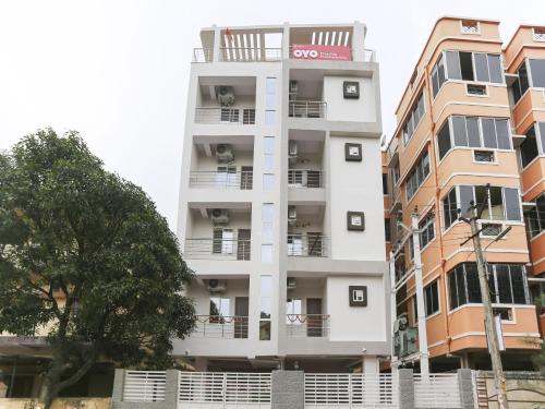 a tall white building with balconies and a tree at Hotel O Prashant Villa in Rānchī