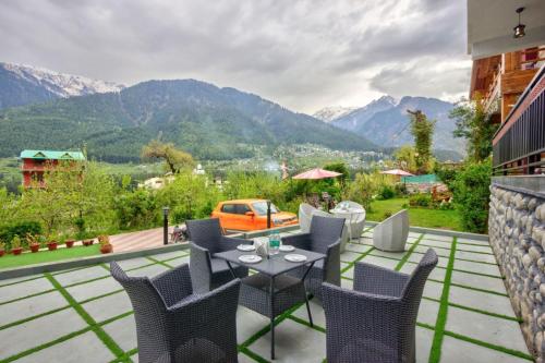 a patio with a table and chairs and mountains at Hotel B2B 2500 Rs With Bkf & Dinner , Mounatin View And Balcony in Manāli
