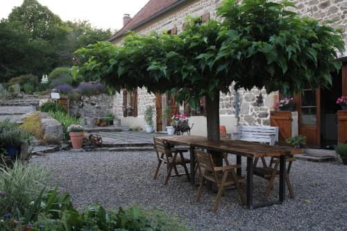 une table et des chaises en bois sous un arbre dans l'établissement La Belle Âme, à Saint-Priest-des-Champs