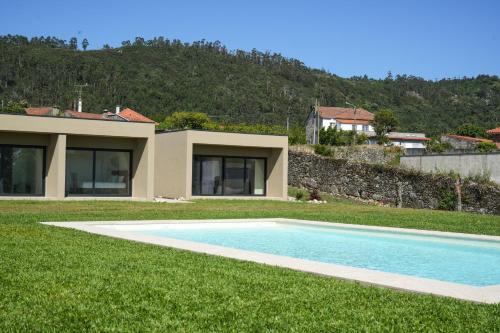 a house with a swimming pool in the grass at Quintinha Pilares da Terra in Marinhas