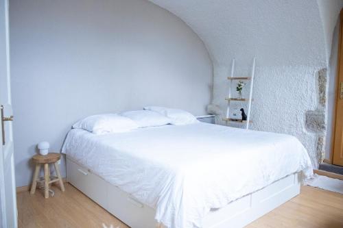 a white bed in a white bedroom with a white wall at Charme rare sous les voûtes in Royat