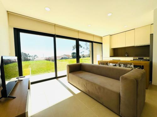 a living room with a couch and a kitchen at Quintinha Pilares da Terra in Marinhas