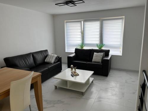 a living room with two black couches and a table at DEDIA Guest Home 