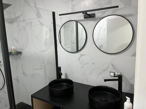 a bathroom with a black sink and two mirrors at DEDIA Guest Home 