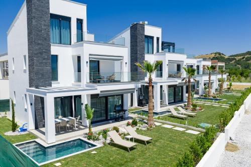 a large white villa with a swimming pool and palm trees at Olympiada Residential Complex & Villas in Ofrínion