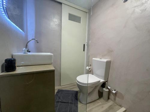 a bathroom with a white toilet and a sink at The Obsidian Suite , next to Heraklion Airport in Heraklion