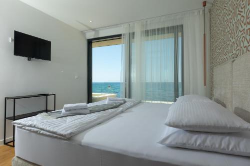 a white bedroom with a large bed with a large window at Adria Resort SEAFRONT Villa C Private Pool Pet Friendly in Zaton
