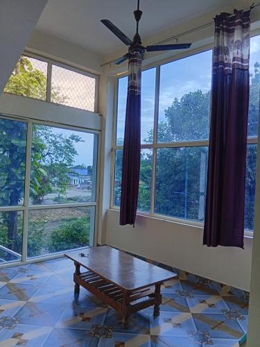 a living room with windows and a wooden table at Corbett view homestay in Belparāo