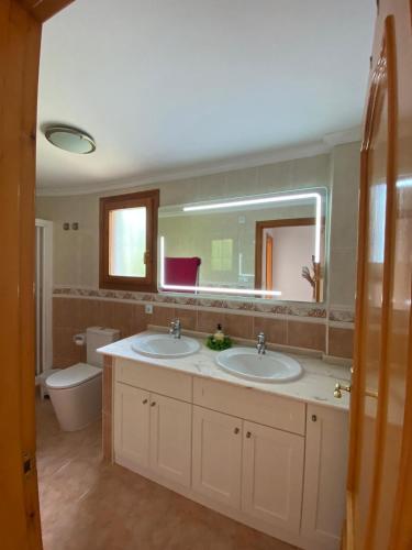 a bathroom with two sinks and a toilet and a mirror at Casa Emilia in Adsubia