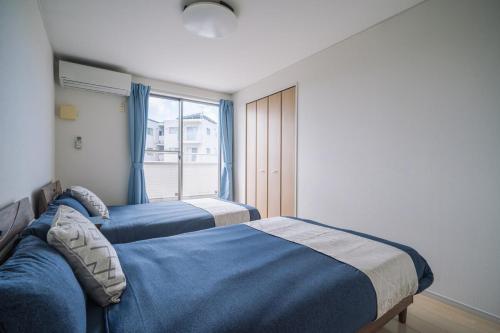 two beds in a room with a window at Comfort Miyabi -4号棟 in Yomitan